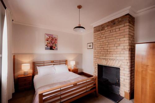 ein Schlafzimmer mit einem Bett und einem gemauerten Kamin in der Unterkunft Workers cottage on Wellington in Hobart