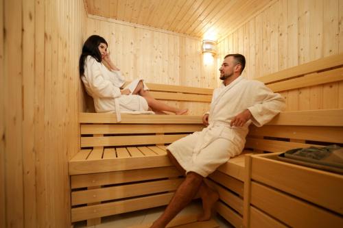 a man and woman sitting in a sauna at Nest Suites in Skopje
