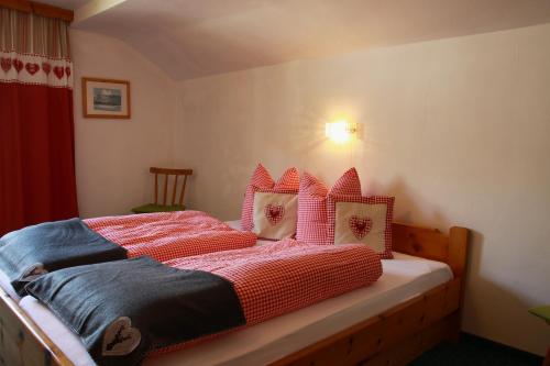a bedroom with a bed with red sheets and pillows at Ferienhaus Carmen in Grän