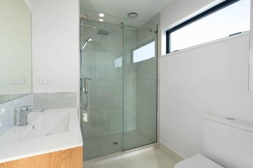 クライストチャーチにあるBrand New Close to CBD 3 Bed 3 Bath with Garageのバスルーム(ガラス張りのシャワー、シンク付)