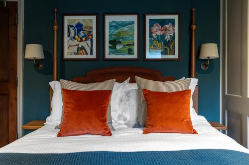 a bedroom with a bed with blue walls and orange pillows at The Griffin Inn in Fletching