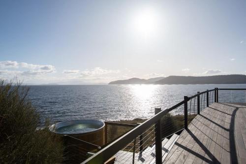 a hot tub sitting on a dock next to a body of water at Siren Tasmania in White Beach