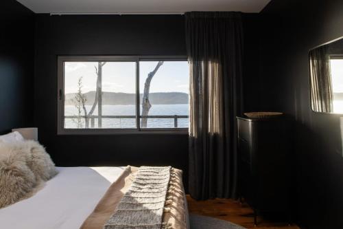 a bedroom with a bed and a large window at Siren Tasmania in White Beach