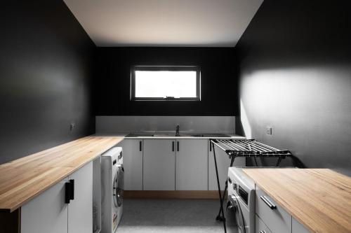 a kitchen with white cabinets and a sink and a window at Siren Tasmania in White Beach
