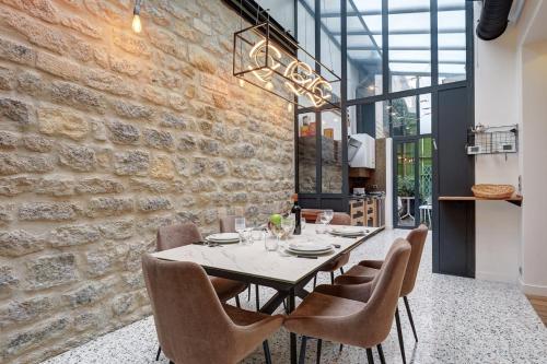une salle à manger avec un mur en pierre, une table et des chaises dans l'établissement 334 Parisian Loft - Superb Apartment in Paris, à Paris