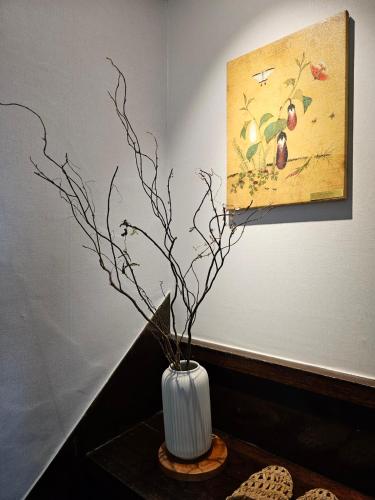 a white vase with branches in it on a table at Soban Stay in Busan