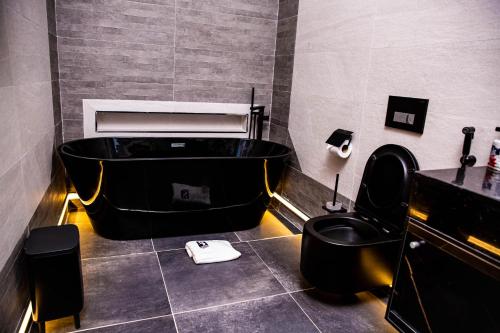 a bathroom with a black tub and a black toilet at The Stallion Abuja in Abuja