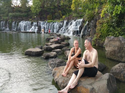 a man and woman sitting on rocks in front of a waterfall at Cat Tien Jungle Lodge in Cat Tien