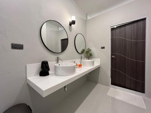 un bagno bianco con lavandino e specchio di Vacanza Home Betong วาคานซ่า โฮม เบตง a Ban Komo Sip Paet