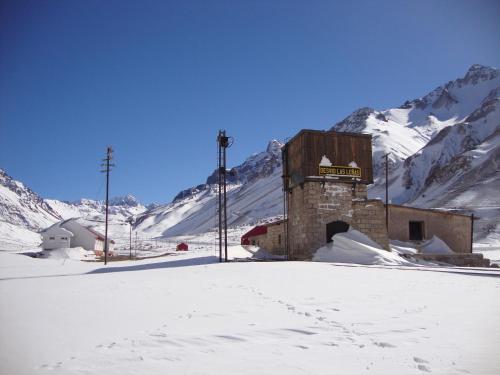 a building in the snow with mountains in the background at Hospedaje Leñas del Tolosa in Las Cuevas