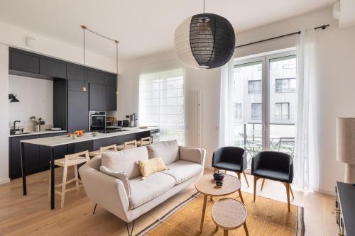 un salon avec un canapé et une cuisine dans l'établissement Le Bacchus - Charmant appt avec vue sur la Vilaine, à Rennes