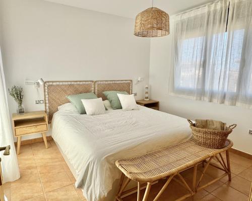 ein Schlafzimmer mit einem großen Bett mit einem Stuhl und einem Fenster in der Unterkunft Villa Majanicho con piscina in Lajares