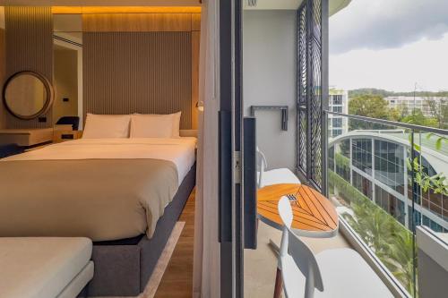 a bedroom with a bed and a balcony at La Green Hotel and Residence in Bang Tao Beach