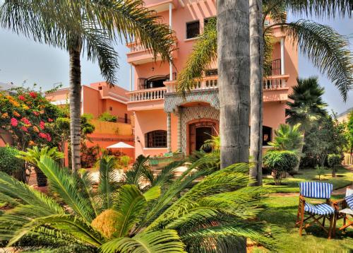 a pink building with palm trees in front of it at LHOSTEL à Casablanca in Casablanca