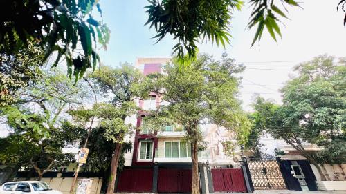 a house with a red fence and trees in front at Olive Serviced Apartments - New Friends Colony in New Delhi