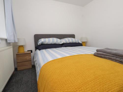 a bedroom with a bed with a yellow blanket at Sea Cliff in Pwllheli