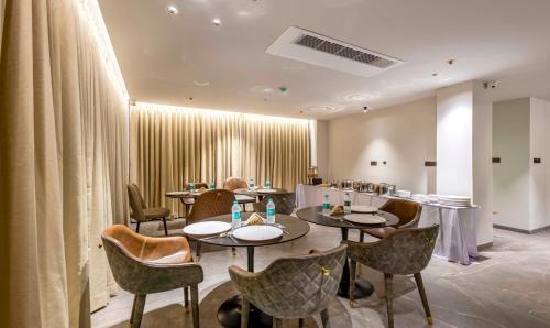 a dining room with tables and chairs and curtains at Treebo Premium Lalitha, RK Beach in Visakhapatnam