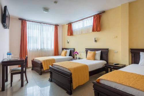 Habitación de hotel con 2 camas y mesa en Hotel Flamingo, en Puerto Ayora