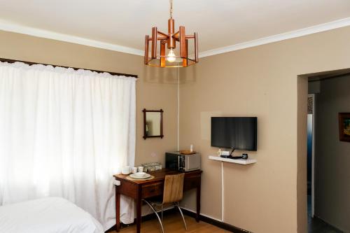 a bedroom with a bed and a desk with a television at STAY In TEHAMA in Cape Town
