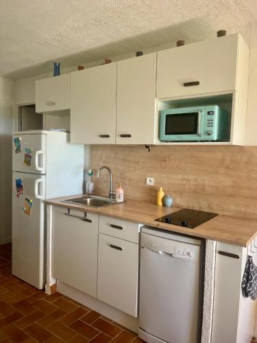 une cuisine avec des armoires blanches, un évier et un réfrigérateur dans l'établissement Les Issambres, appt accès direct plage sable, idéal 4 pers, vue mer, Clim, à Roquebrune-sur Argens