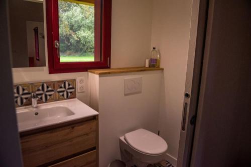 une salle de bain avec un lavabo et des toilettes et une fenêtre dans l'établissement la maison des Poteries, à Chanteloup-les-Bois