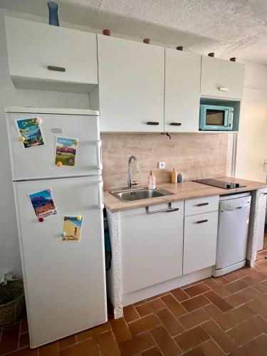 une cuisine avec un réfrigérateur blanc et un évier dans l'établissement Les Issambres, appt accès direct plage sable, idéal 4 pers, vue mer, Clim, à Roquebrune-sur Argens