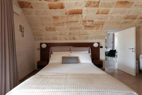 a bedroom with a large bed with a brick wall at Masseria Misocampo - Happy Rentals in Calimera