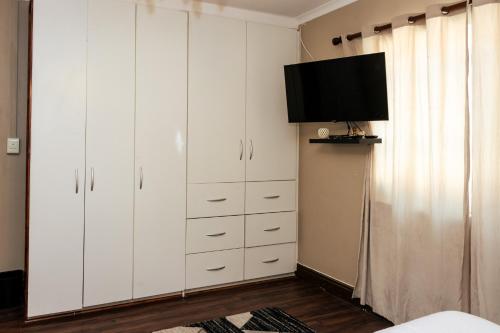 a bedroom with white cabinets and a flat screen tv at STAY In TEHAMA in Cape Town