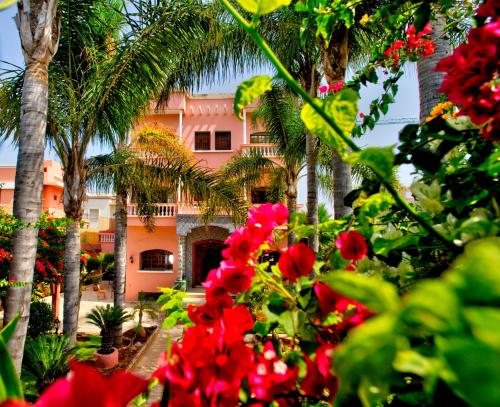 a pink building with palm trees and red flowers at LHOSTEL à Casablanca in Casablanca