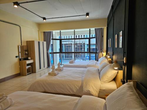 a hotel room with four beds and a large window at My Home Central Hatyai - Whole house - 18pax in Sathani Khlong Rian
