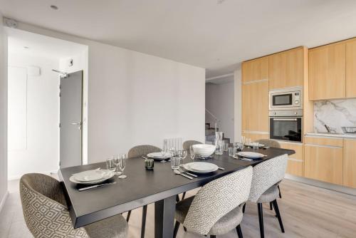 une salle à manger avec une table et des chaises noires dans l'établissement 157 Suite Sacha - Superbe Duplex à Paris, à Paris