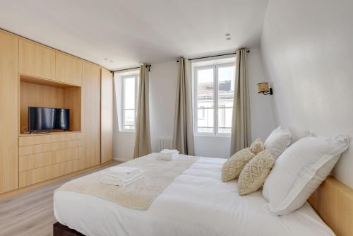 - une chambre avec un grand lit blanc et une télévision à écran plat dans l'établissement 157 Suite Sacha - Superbe Duplex à Paris, à Paris