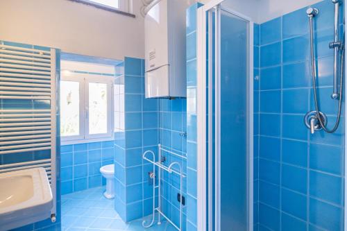 a blue bathroom with a shower and a sink at Case Schiaffino by Wonderful Italy in Laigueglia