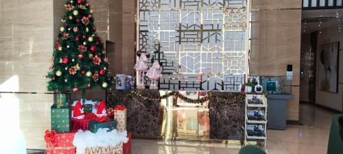 a christmas tree in a lobby with presents under it at 2 BR Apartment Grand Jati Junction Medan view City 12th Floor in Medan