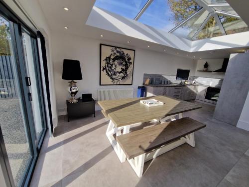 a living room with a table and a room with windows at Modern & Spacious 5 Bedroom Bungalow with Parking Near Brecon Beacons & Bike Park Wales in Cefn-coed-y-cymmer