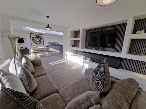a living room with a couch and a tv at Modern & Spacious 5 Bedroom Bungalow with Parking Near Brecon Beacons & Bike Park Wales in Cefn-coed-y-cymmer