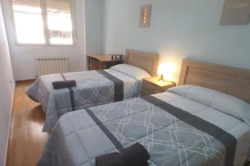 una camera da letto con due letti e una lampada su un tavolo di Apartamento con 3 dormitorios y plaza de garaje a Tudela de Duero
