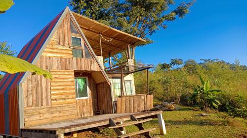 a wooden cabin with a bench in front of it at ไร่นิธิสุนทร nithisoonthon farmstay in Mae Hong Son