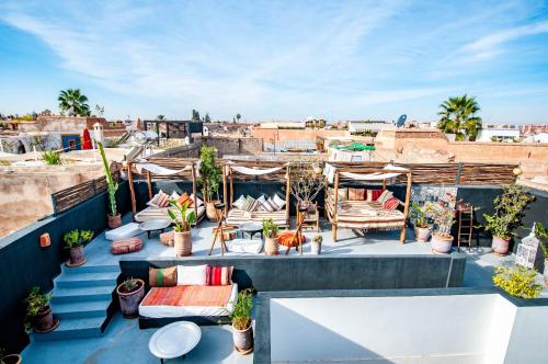 a rooftop patio with chairs and potted plants at Riad Origines in Marrakech