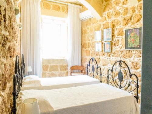 two beds in a room with a stone wall at Nuffara - a charming traditional Farmhouse with a large pool in Xagħra