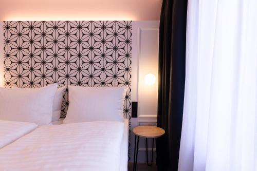 a bedroom with a white bed with a black and white headboard at Garner Hotel Mannheim City by IHG in Mannheim