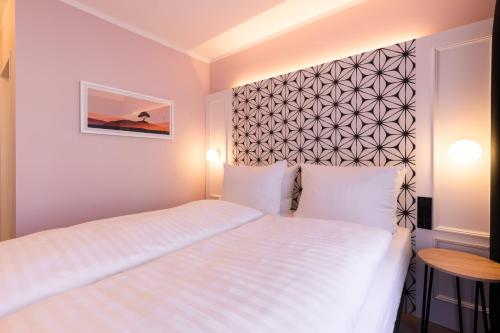 a bedroom with a white bed and a wall at Garner Hotel Mannheim City by IHG in Mannheim