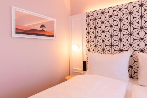 a bedroom with a white bed and a picture on the wall at Garner Hotel Mannheim City by IHG in Mannheim