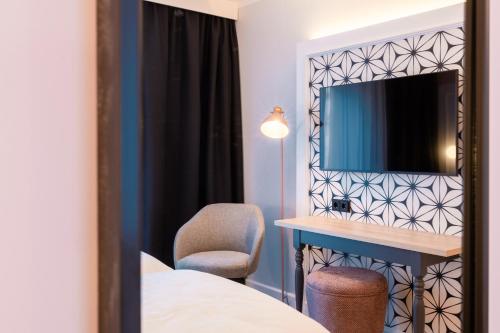 a room with a bed and a desk and a mirror at Garner Hotel Mannheim City by IHG in Mannheim