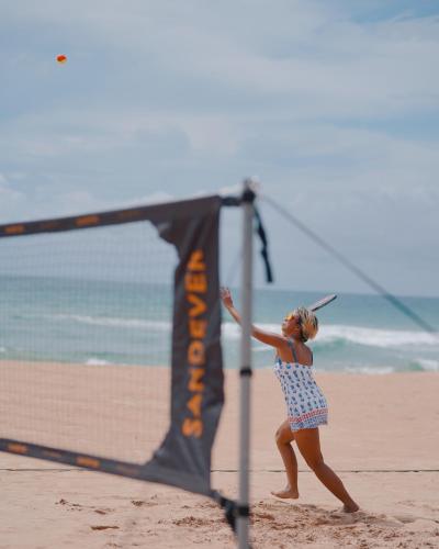 a woman is playing volleyball on the beach at Nyne Hotels Rock Villa - Bentota in Bentota