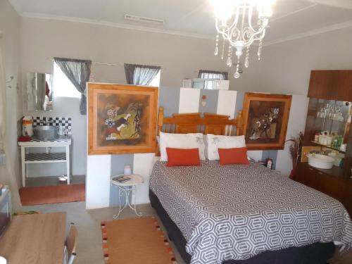 a bedroom with a bed with orange pillows and a chandelier at Karoo Pomp in Vosburg