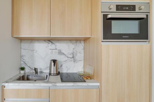 une cuisine avec un évier et un micro-ondes dans l'établissement 158 Suite Jeremy - Superbe Appartement à Paris, à Paris