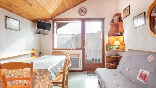 Cette chambre comprend une table, un canapé et une fenêtre. dans l'établissement VISONS - 11 - Studio Mezzanine 6 pers, à Saint-Sorlin-dʼArves