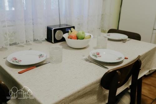 a table with plates and a bowl of fruit on it at Kuća za odmor Proljeće in Ðakovo