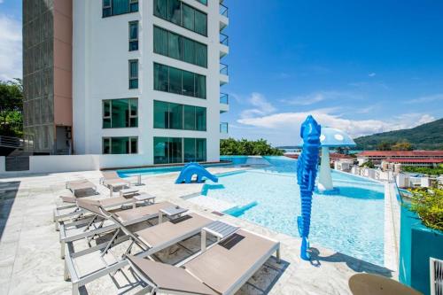 a swimming pool with lounge chairs and a blue infront of a building at Deluxe Twin Bed Apartment by Renttini in Kamala Beach